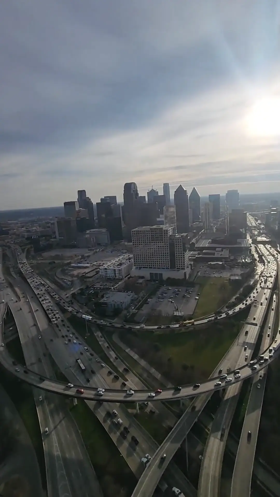 Aerial view of a city skyline and highway interchanges seen from a helicopter in flight with the sun low on the horizon