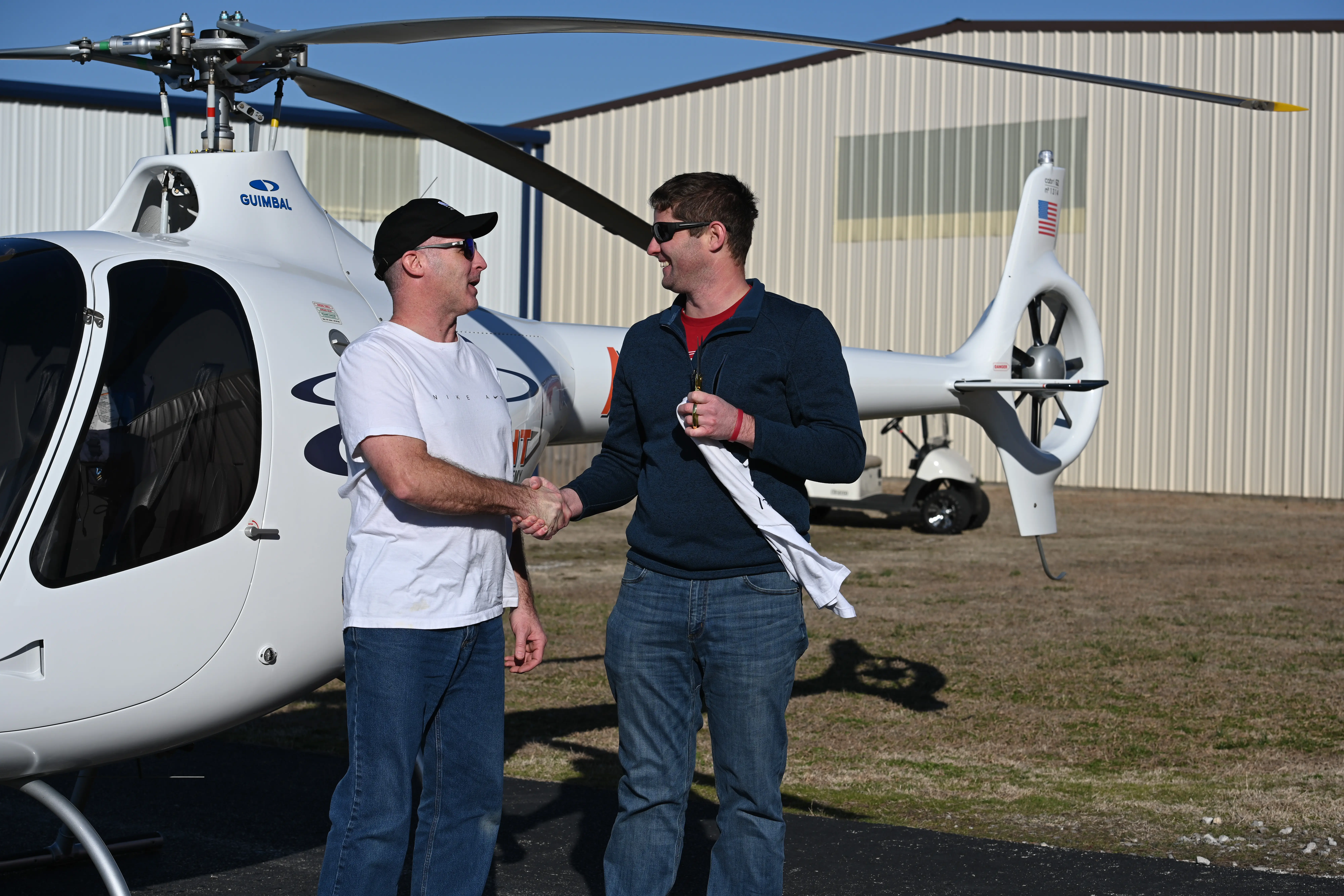 Two men shaking hands in front of helicopter