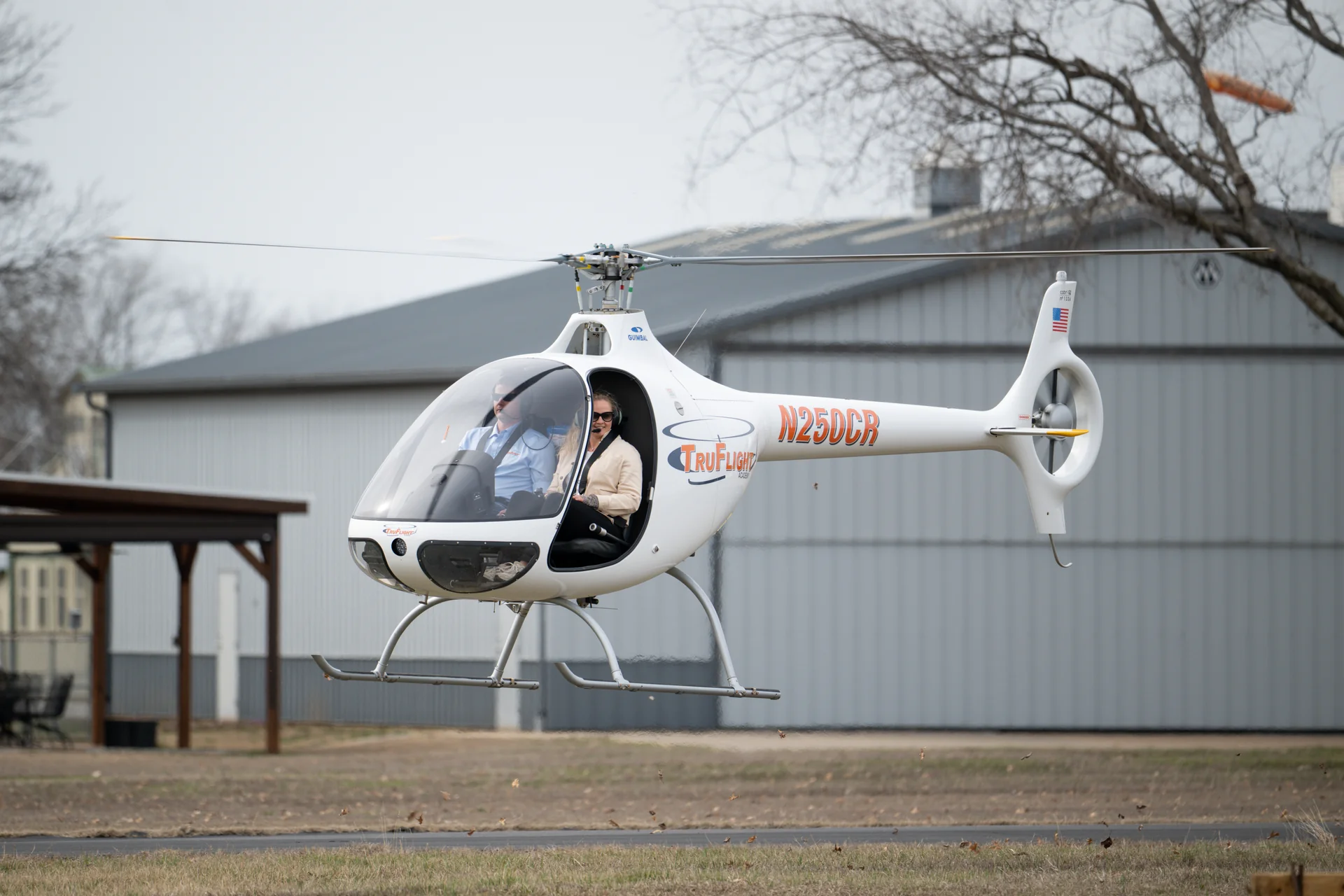 Student and instructor seated in a Cabri G2 helicopter hovering over a field