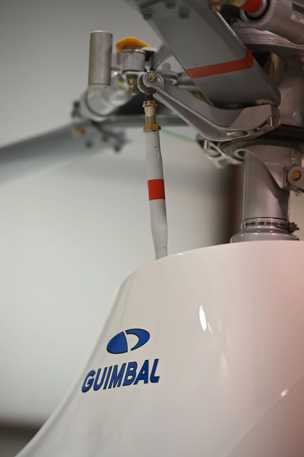 Close view of the main rotor head and Guimbal-branded cowling of a helicopter