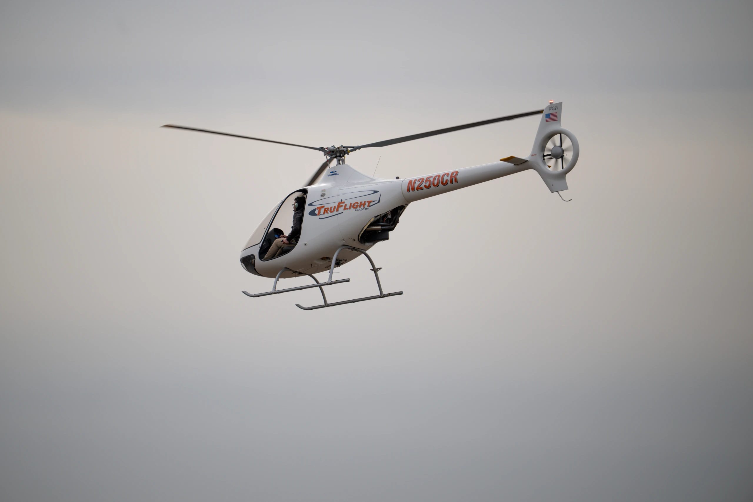 TruFlight Cabri G2 helicopter in flight against an overcast sky